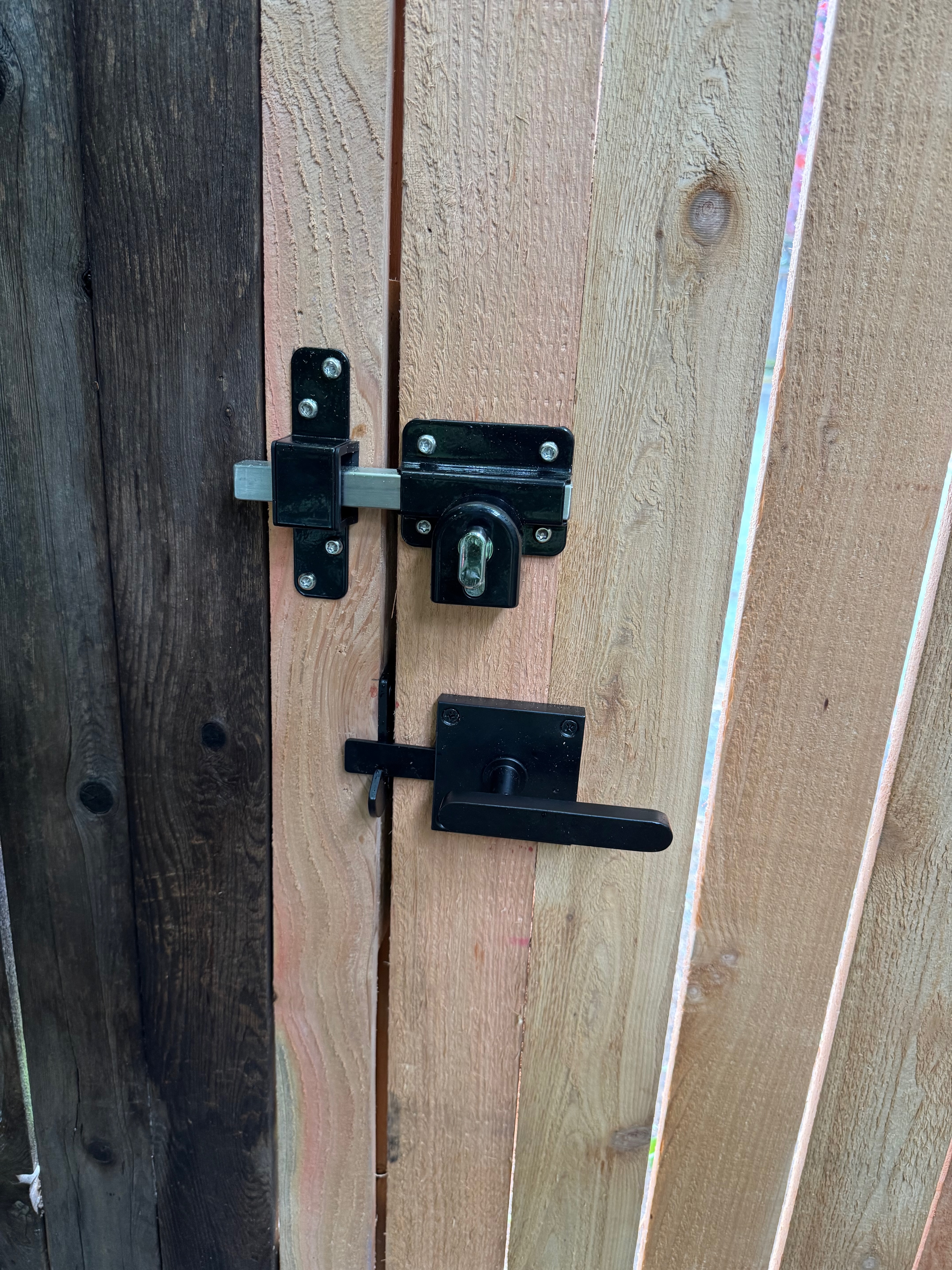 Close-up of the GateMate Long Throw Gate Lock installed on a cedar gate, showing the keyed exterior cylinder and interior turn knob